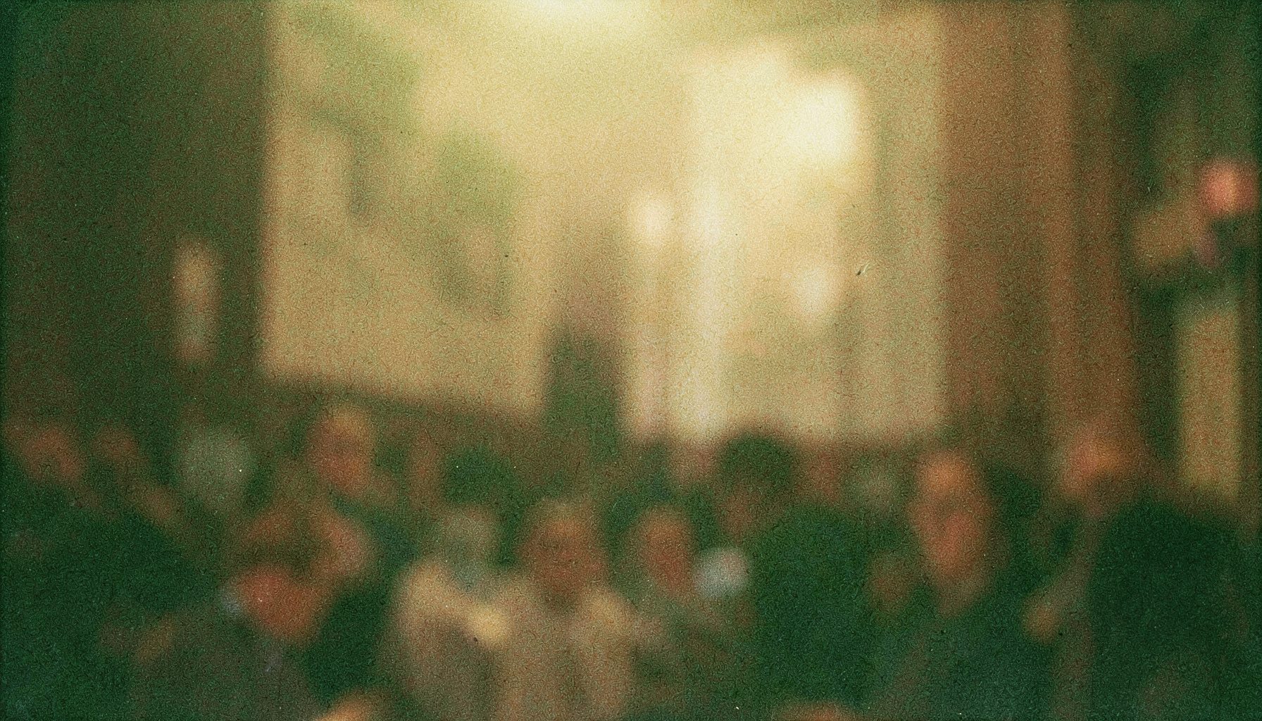 Аналоговая фотография с заметным зерном: тёплый приглушённый свет, винтажная атмосфера, мягкие коричневые и золотистые тона, размытый фон в стиле старого кинозала